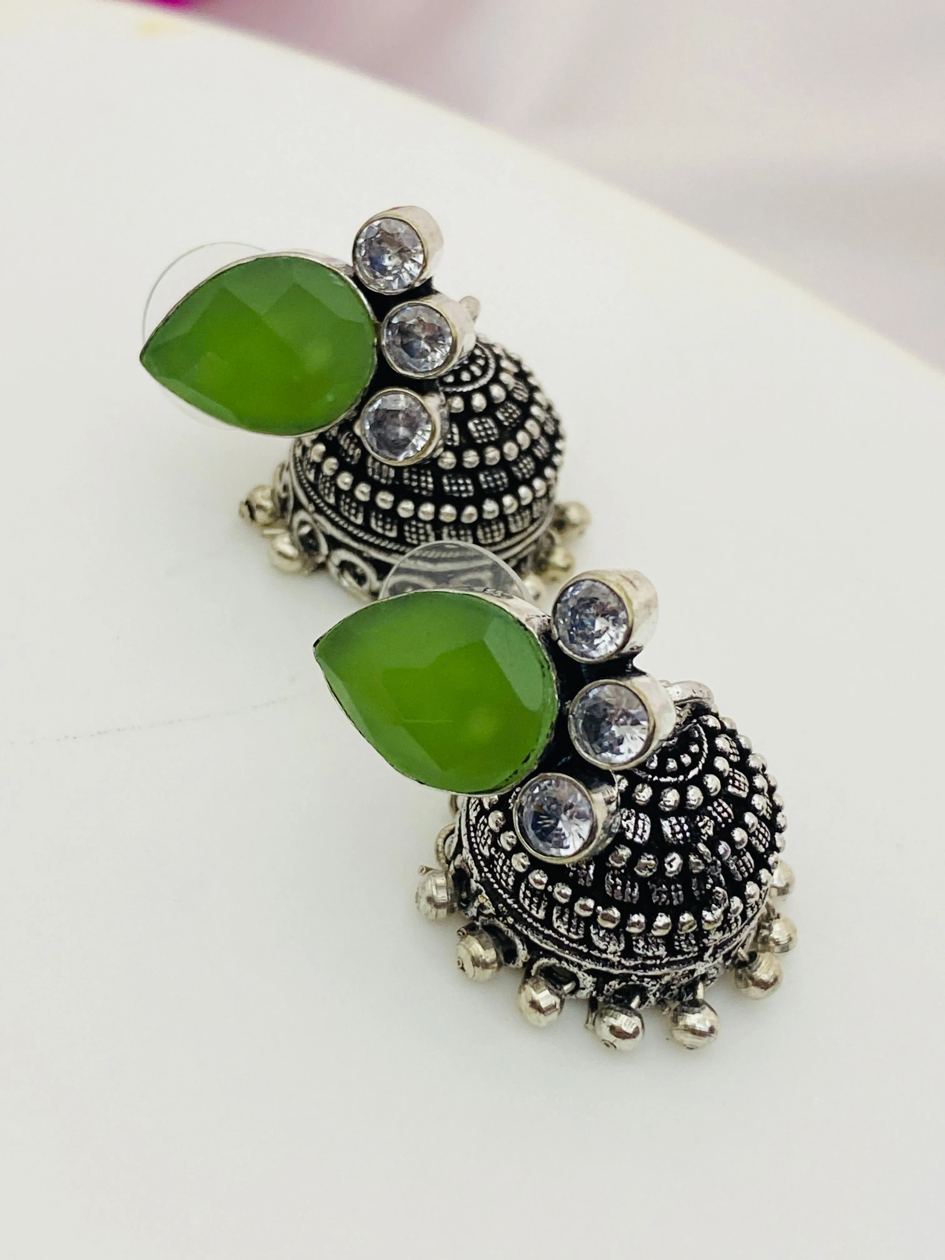 Lovely Green AD Stone Beaded Silver Toned Designer Jhumka Earrings With Black Pearl Drops